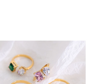 Dettaglio di anelli minimalisti placcati in oro con gemme verdi e rosa brillanti