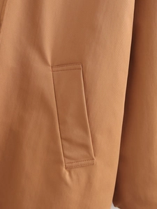 Detail showing diagonal pocket and fine stitching on a brown twill cotton jacket
