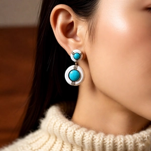 Gros plan d'une boucle d'oreille vintage en or avec cercles blanc et turquoise et diamants
