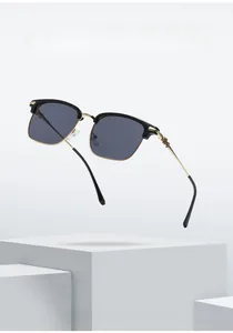 Detailed view of black and gold square frame sunglasses with floral engraving on the temples