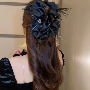 Détail de la pince à cheveux en velours avec plumes noires et pendentif en cristal