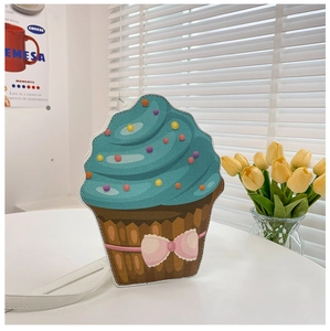 Detail of creative cupcake shaped crossbody bag with blue icing and pink bow decoration