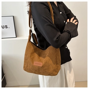 Detailed close-up of brown corduroy tote bag with fashion leather tag and charm