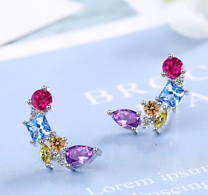 Macro shot of silver studs set with colorful round red and square blue cubic zirconia
