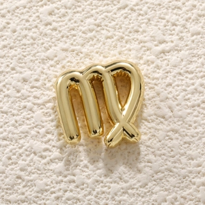 Close-up of golden Virgo zodiac pendant charm on a textured stone surface