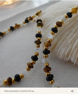 Macro view of Tiger Eye stone beads with gold spacers on white shell texture