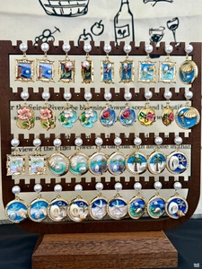 Detailed close-up of retro enamel pearl earrings featuring vintage floral and ocean art