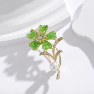 Macro shot of green enamel flower brooch with rhinestones and white pearl accent