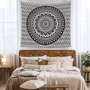 Black and white mandala tapestry used as a decorative wall hanging in a cozy bedroom