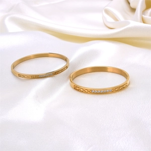 Detail view of gold stainless steel bangles with rhombic pattern and single row zircon
