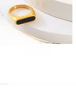 Detail of minimalist gold ring with rectangular black enamel inlay on white stone