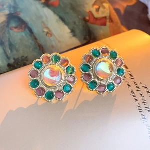 Macro detail of vintage floral earring with green crystals on antique book pages