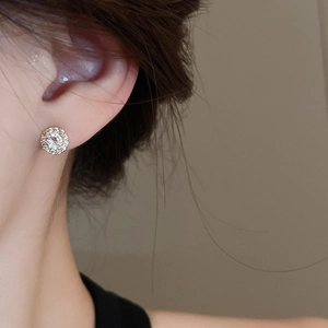 Close-up of a silver halo stud earring with zircon inlay worn on a woman's earlobe