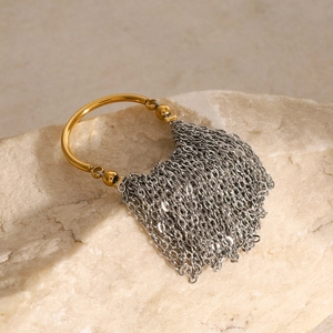 Macro detail of gold ring with silver chain tassels on natural stone surface