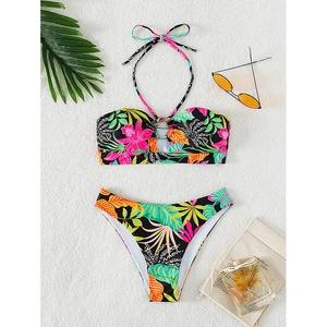 Women's two-piece floral bikini set with halter top and tropical print on white beach sand