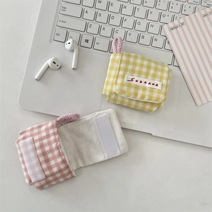 Detalle de la mini bolsa para auriculares con cierre de velcro y tejido de cuadros