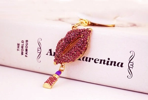 Detail of purple rhinestone lip keychain with a lipstick pendant on white book