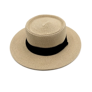 Detailed close-up of wide brim boater hat featuring fine straw weave and black ribbon bow