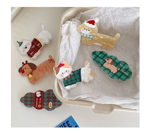 Detailed view of Christmas acrylic hair clips with dog, cat, and tree motifs on a gift tray