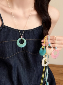 Close-up showing colorful marble-effect resin pendants on various colored cord necklaces