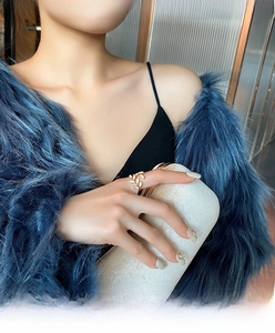 Close-up of golden leaf open ring on model hand with blue fur coat and handbag
