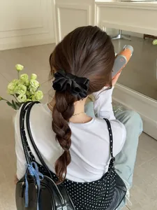Détail d'un nœud papillon en satin noir coiffé sur une tresse brune pour un look élégant