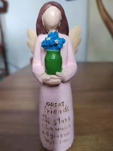 Detail of hand-painted resin angel statue with blue flowers and friendship quote