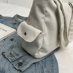Beige corduroy tote bag for women with front flap pocket on a blue denim jacket