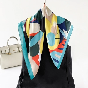 Detail of colorful silk square scarf with vibrant prints styled on a white handbag