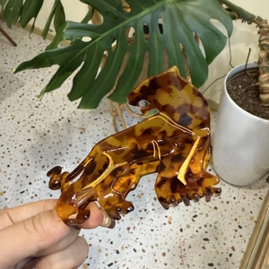 Detail view of a leopard-shaped amber hair claw clip with animal print texture