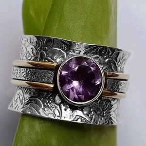 Macro detail of vintage silver ring with floral relief and round faceted purple amethyst