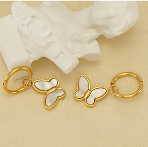 Vue détaillée de boucles d'oreilles papillon dorées avec nacre sur fond texturé