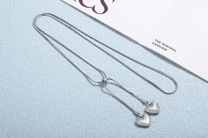 Macro detail of silver snake chain necklace with heart pendants and adjustable slider