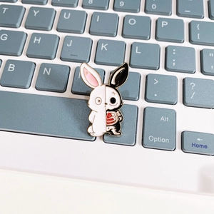 Detail of a rabbit enamel pin with a split black and white skeleton design on a keyboard