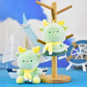 Detailed view of two cute green dragon plush keychains with yellow scarves in a nautical scene