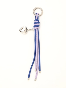 Detail of blue and purple braided leather keychain with silver heart pendant on white background