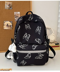 Detail of black butterfly canvas backpack with plush charm and stylish printed patterns