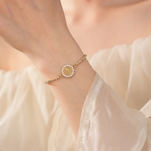 Vue macro du bracelet doré à perles avec médaille de la Vierge Marie et zircons