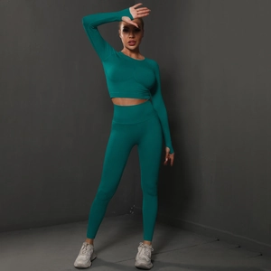 Close-up of seamless yoga set with long sleeve crop top and high waist leggings in dark teal