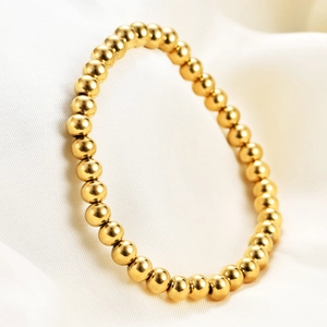 Minimalist 15mm golden stainless steel beaded stretch bracelet on white silk