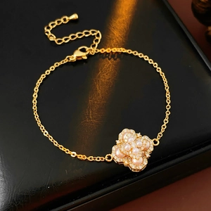 Détail d'un bracelet trèfle plaqué or avec perles et strass sur un support en cuir noir
