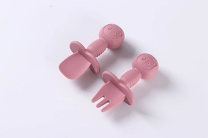 Detail of pink silicone baby spoon and fork set with wooden handle and choke guard