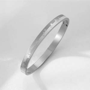 Dettaglio del bracciale in acciaio al titanio con stelle incise e trama spazzolata