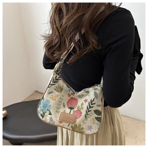 Detailed view of floral embroidery patterns and leather logo on the vintage hobo bag
