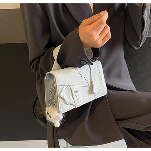 Détail du sac à main en jean bleu clair avec coutures et breloque en peluche blanche