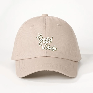Detail shot of Good Vibes white embroidery and crown on beige cotton baseball cap