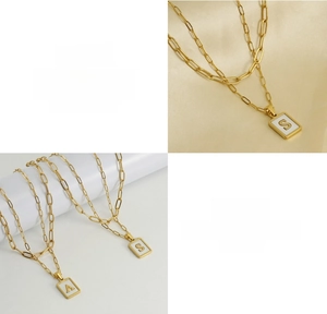 Detail of 18K gold paperclip necklace with square shell inlaid letter S and A pendants