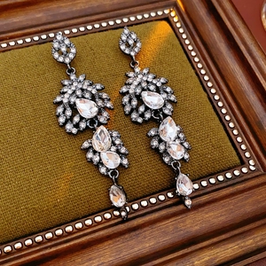 Nahaufnahme von Vintage-Quastenohrringen mit glitzernden Strasssteinen auf grünem Samt
