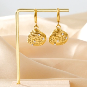 Elegant gold shell earrings with pearl inlays displayed on a professional jewelry stand