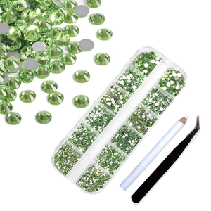 Detail of green flatback nail rhinestones in 12-slot storage box with tools